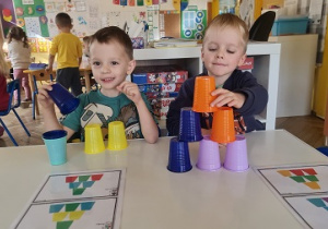 Tymek i Olek budują wieże z kolorowych kubeczków